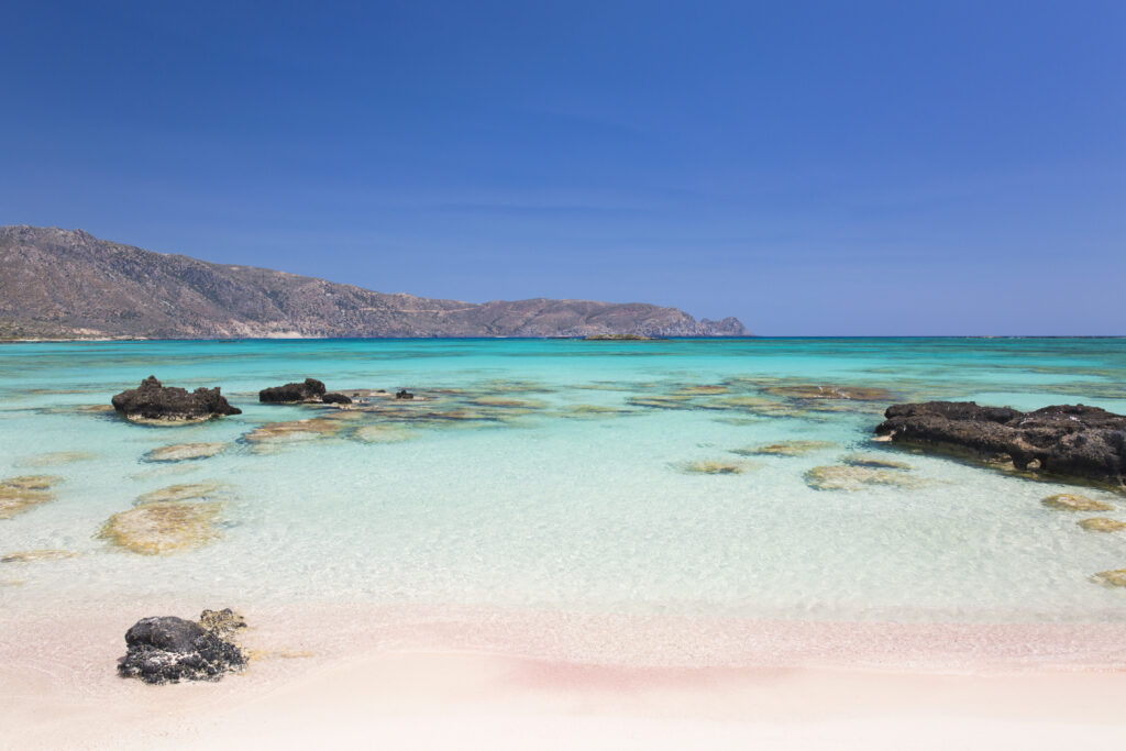 View across the clear turquoise waters of Vroulia Bay from sandy beach, Elafonisi Islet, Elafonisi , Crete, Greece, Europe.