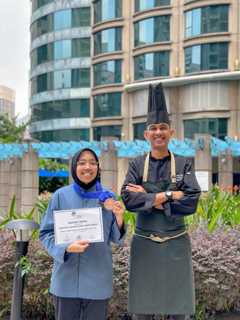 A Marriott Commis 1 associate holding an award with her mentor.