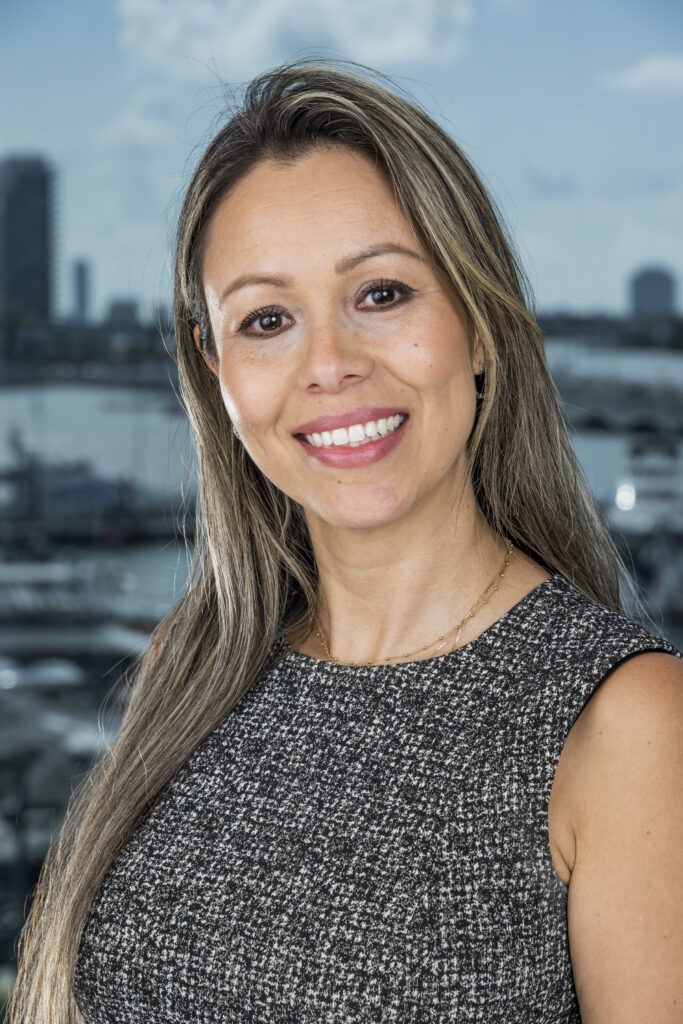 Sandra, Director of Finance, with long hair and a gray top.