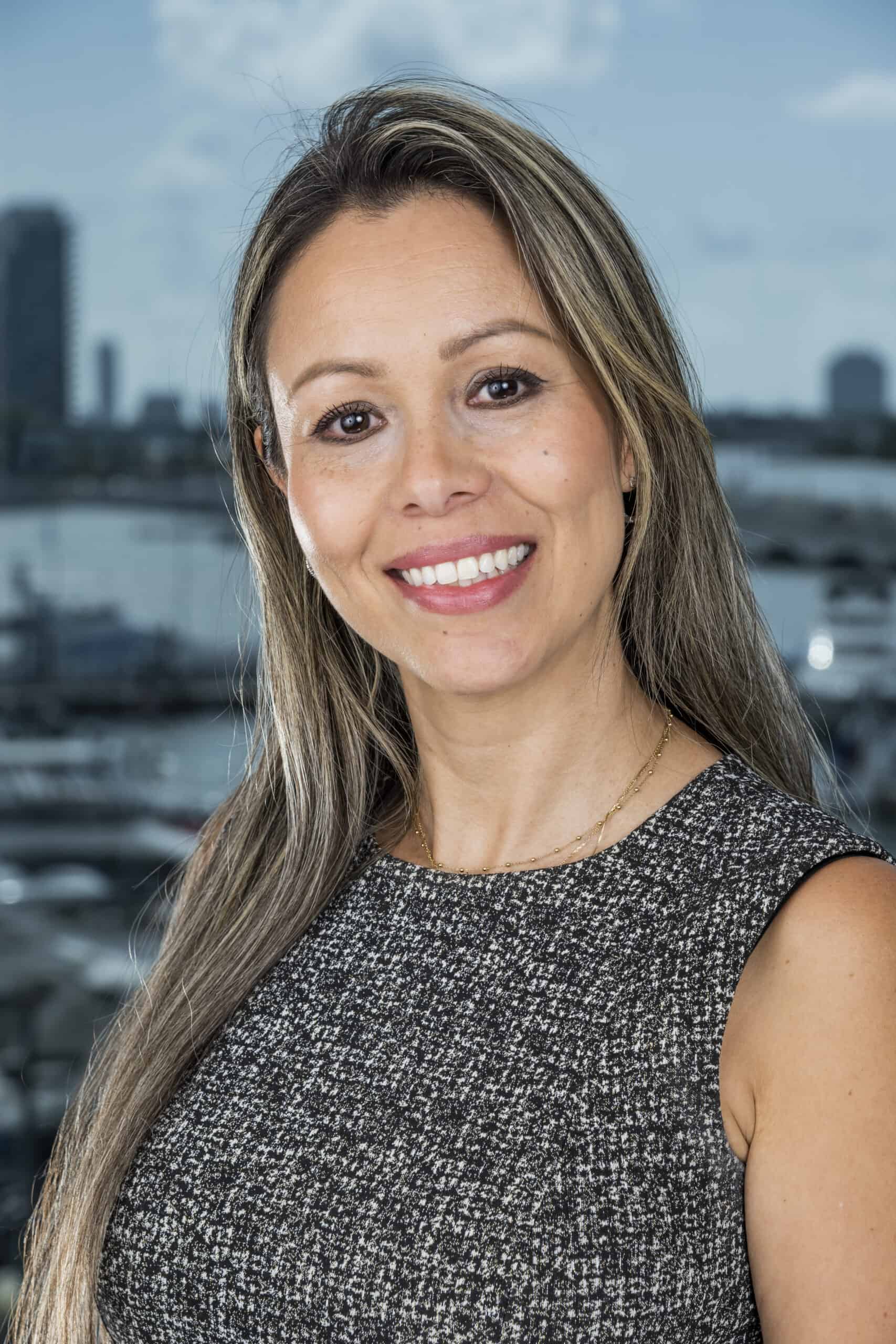 Sandra, Director of Finance, with long hair and a gray top.